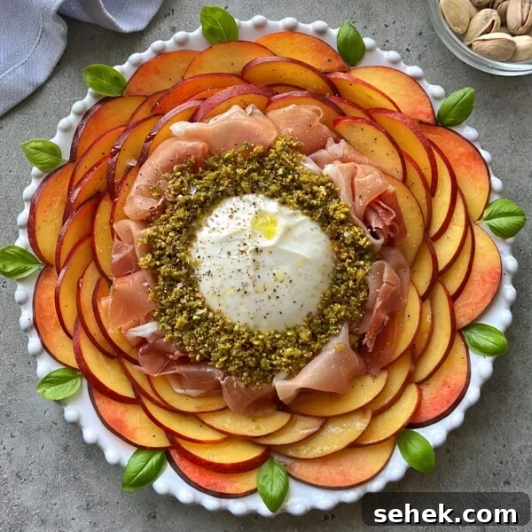 Classic Tomato Caprese Salad with Fresh Basil and Mozzarella 7 A round white plate with concentric layers of sliced peaches and nectarines, prosciutto, and crushed pistachios surrounding a ball of burrata cheese, garnished with basil leaves and a drizzle of olive oil—a refreshing nectarine salad.