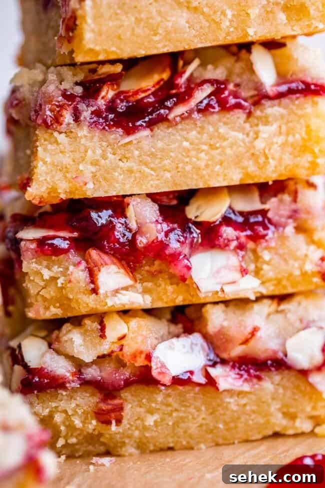 Raspberry Almond Streusel Crumble Bars 10 raspberry crumb bars in a stack topped with almonds and jam.