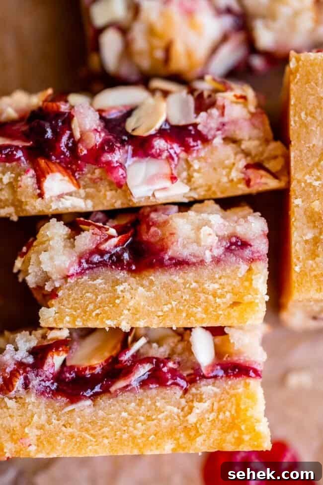Raspberry Almond Streusel Crumble Bars 4 raspberry almond bars stacked up on parchment paper.