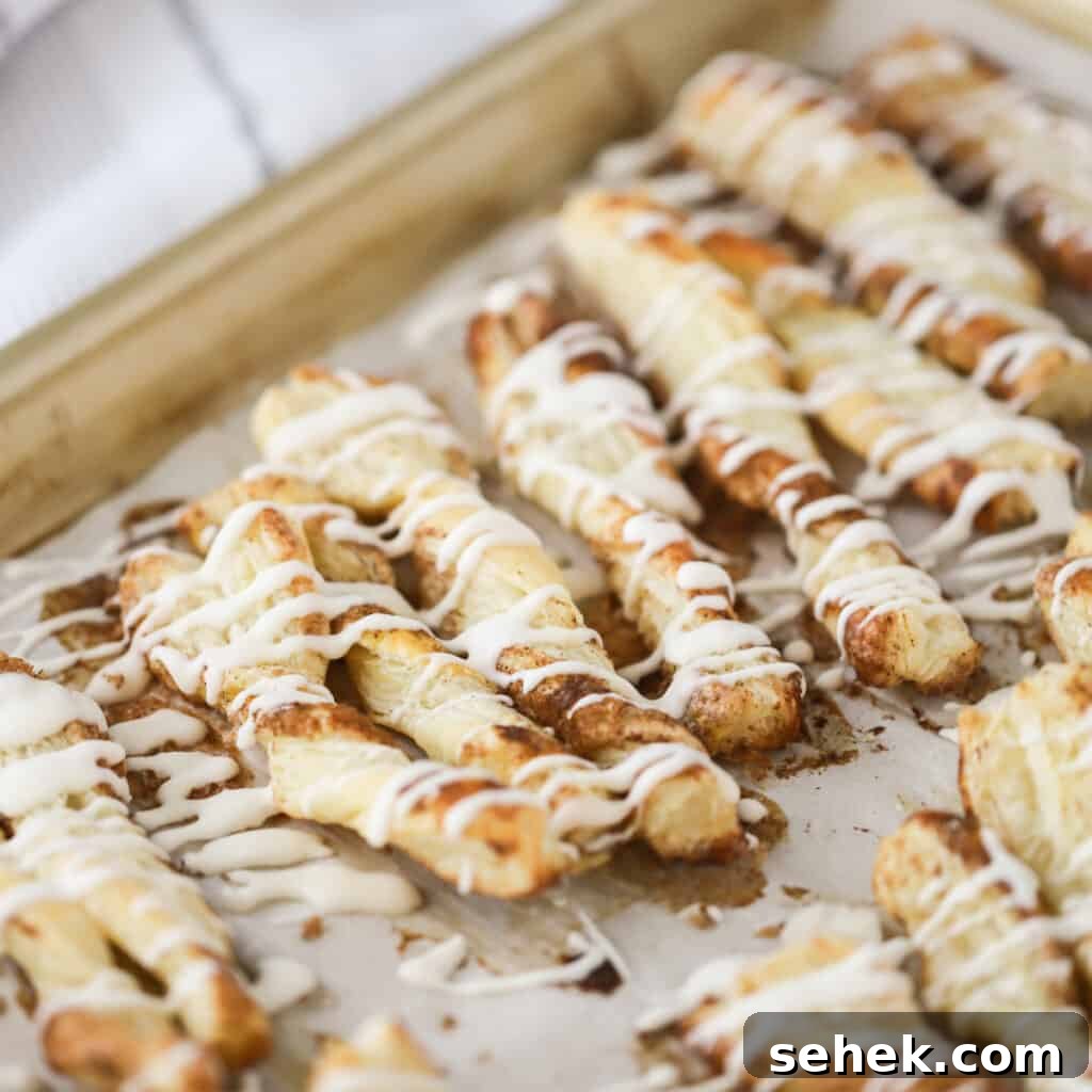 Crispy Cinnamon Puff Pastry Twists: Quick Sweet Pastry Recipe 5 A baking sheet full of cinnamon puff pastry twists drizzled with icing.