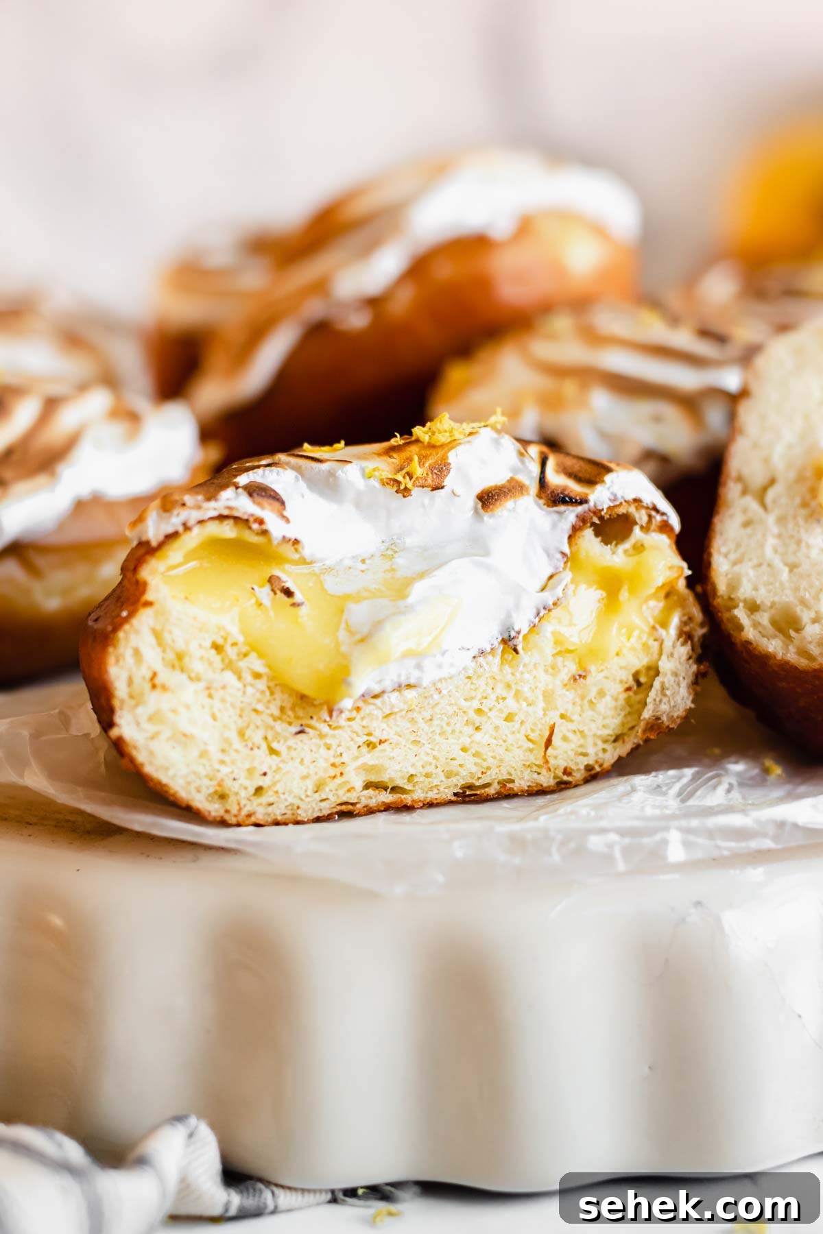 Lemon Meringue-Filled Donuts: Zesty Citrus Cream Puff 2 Straight on shot of the cross section of a lemon filled donut to show the curd inside.