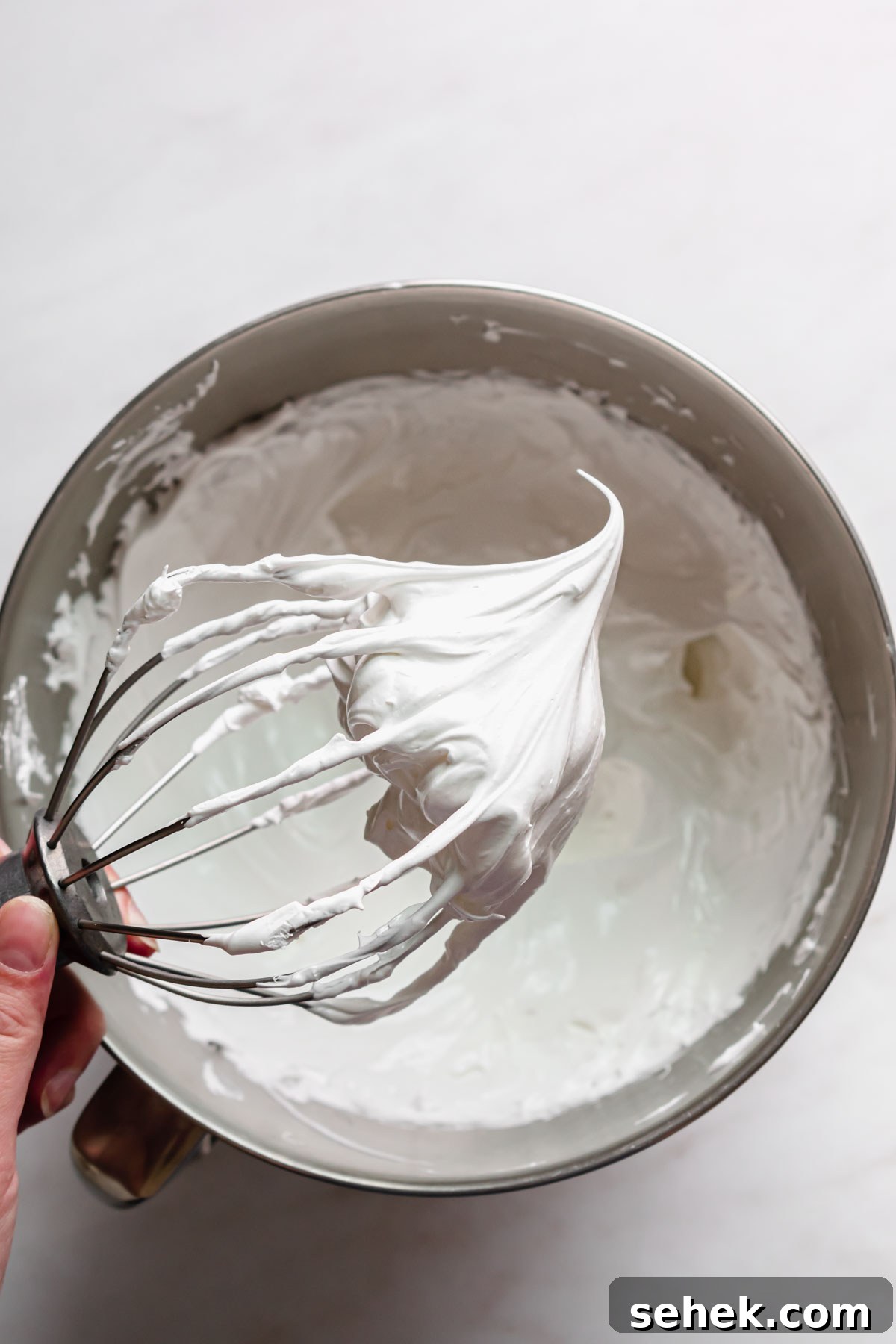 Lemon Meringue-Filled Donuts: Zesty Citrus Cream Puff 12 A whisk held out over bowl to show the stiff swiss meringue.