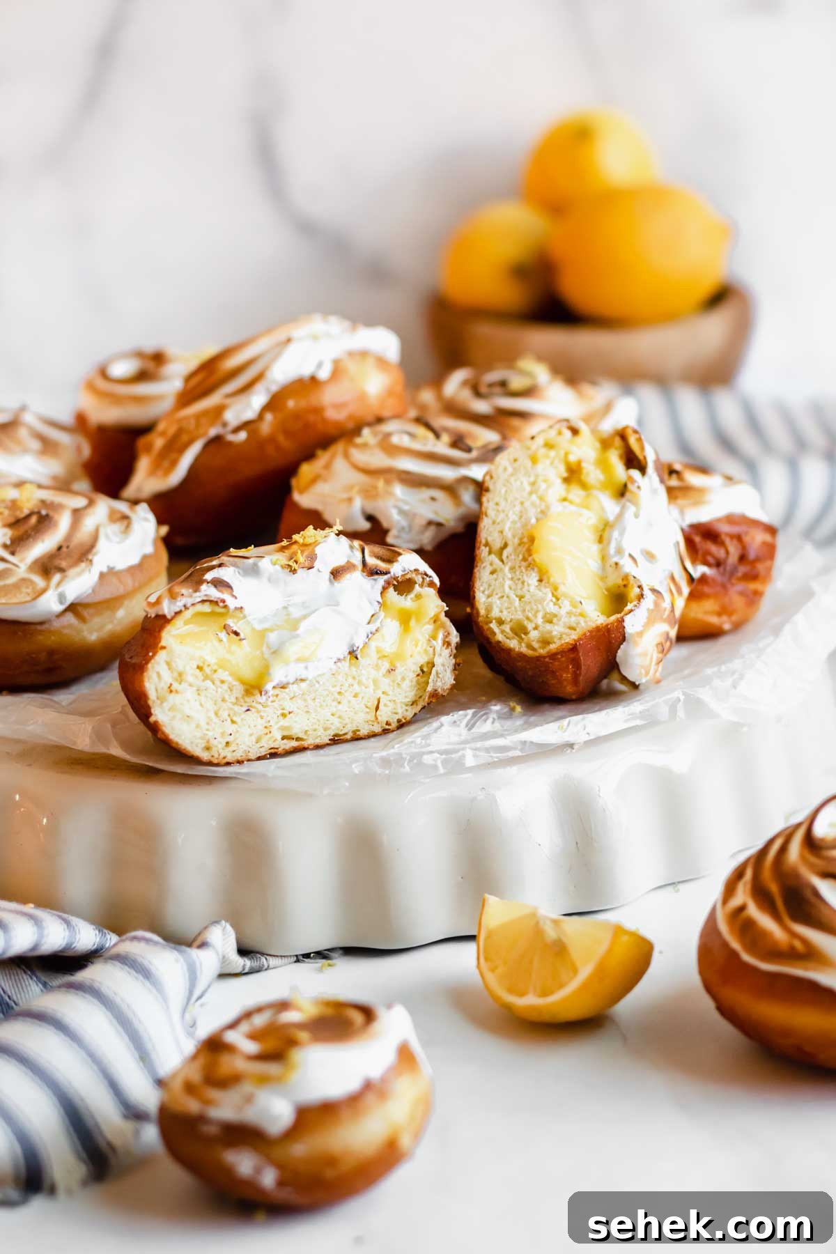 Lemon Meringue-Filled Donuts: Zesty Citrus Cream Puff 17 Straight on shot of a pile of lemon donuts, one is split open.