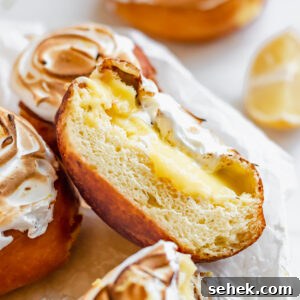 Lemon Meringue-Filled Donuts: Zesty Citrus Cream Puff 18 Close up of a lemon filled donut cut in half to expose the lemon curd and meringue.