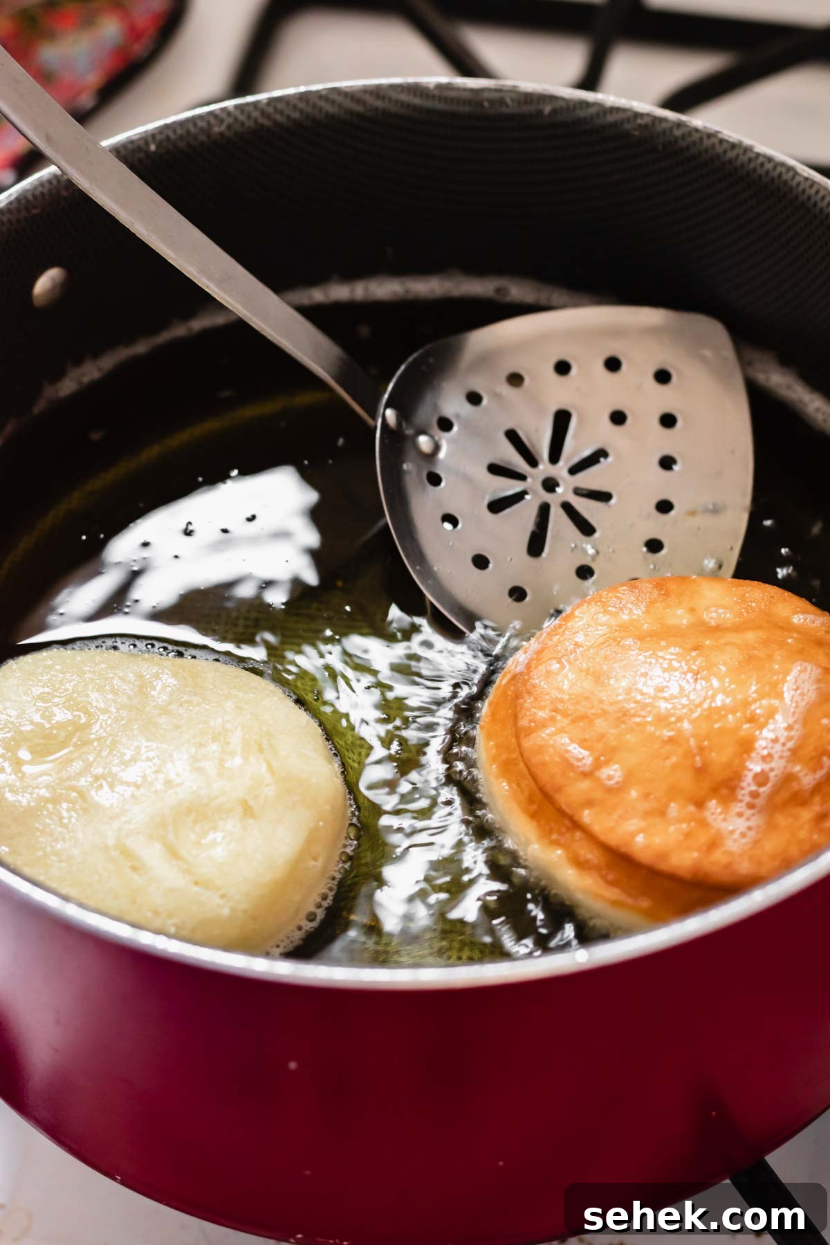 Lemon Meringue-Filled Donuts: Zesty Citrus Cream Puff 10 Donuts in a pot of oil getting fried. One has just been flipped to show the golden color.