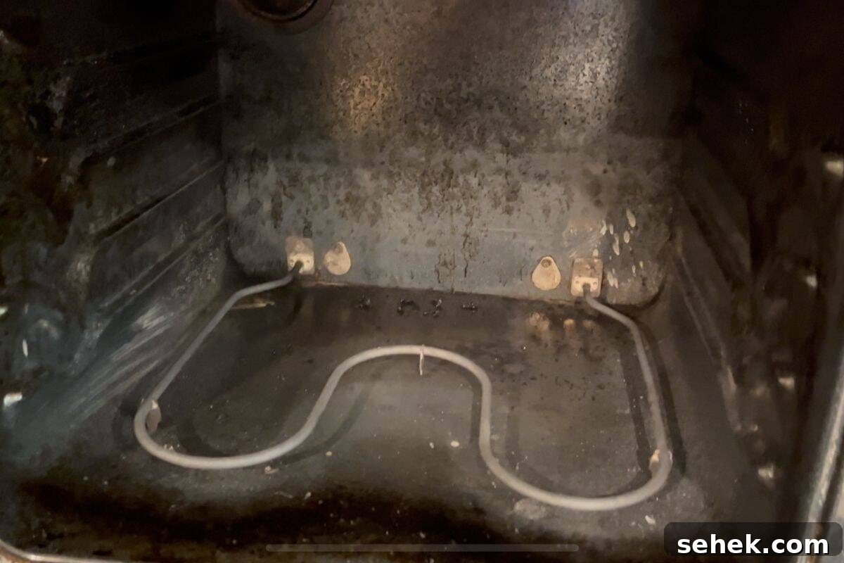 Steam-Clean Your Oven in 2025 Using Simple Kitchen Tools 6 View of the inside of an oven, showing the metal heating element at the bottom and visible grime and stains.