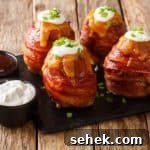 Bacon-Wrapped Volcano Potatoes: Stuffed, Crispy and Gooey 6 Grilled volcano whole potatoes with bacon and cheese served with sauces close-up on the table