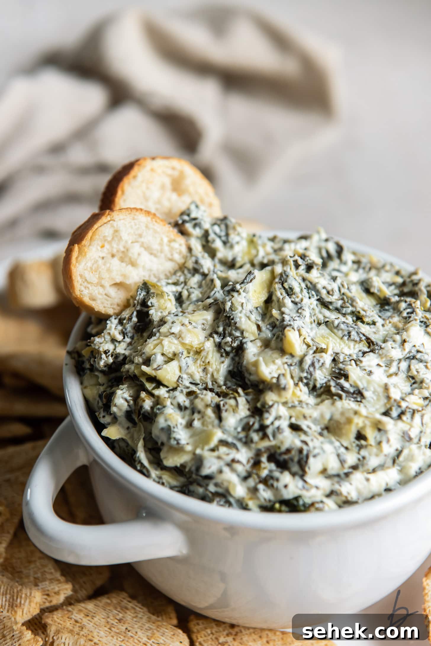 Creamy Slow Cooker Spinach Artichoke Dip Recipe 6 two pita chips in spinach artichoke dip in white bowl with handles