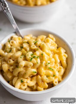 creamy mac and cheese in a white bowl with a spoon.