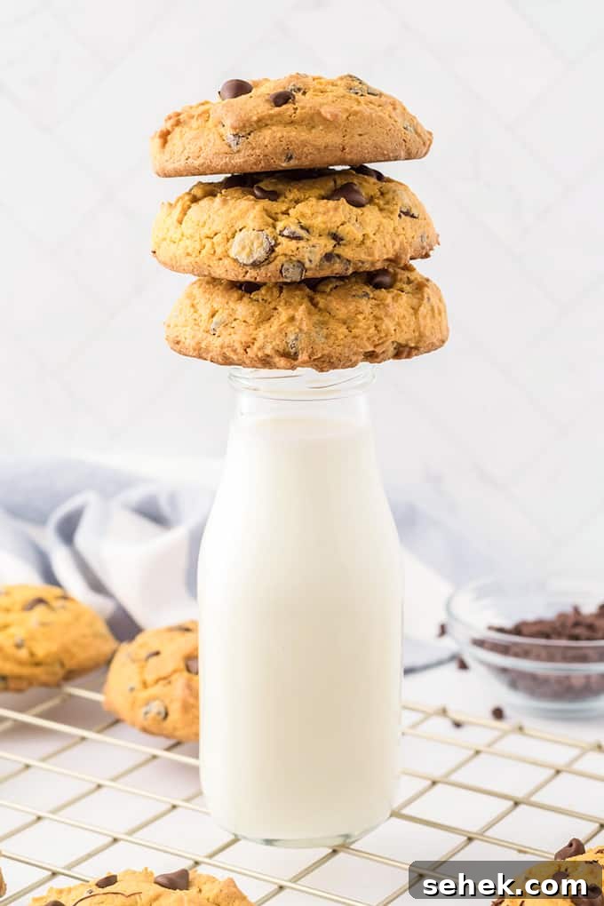 Three cream cheese chocolate chip cookies stacked on a milk jar.