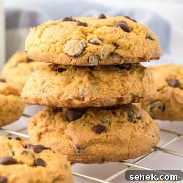 Four cream cheese chocolate chip cookies stacked on a cooling rack.