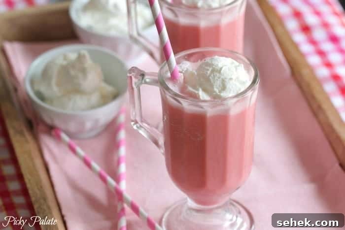 Essential Summer Drinks You Need This Season 4 Two pink strawberry milk slushies side-by-side, topped with ice cream.