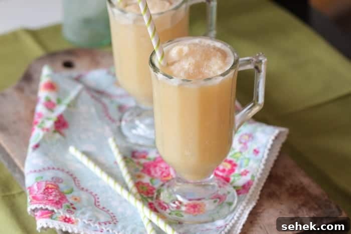Essential Summer Drinks You Need This Season 5 Two side-by-side honey and orange creamsicle slushies on a floral cloth, with straws.