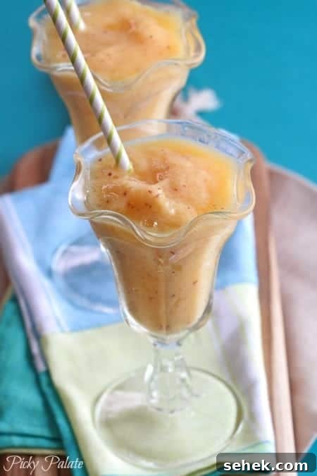 Essential Summer Drinks You Need This Season 7 A mango peach slushy in a fountain glass with a straw.