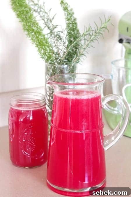 Essential Summer Drinks You Need This Season 8 A clear pitcher of blueberry lemonade next to a full glass.