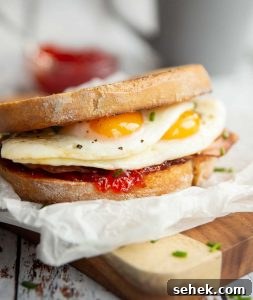 sandwich on wooden chopping board with chilli jam and grey mug blurred in background