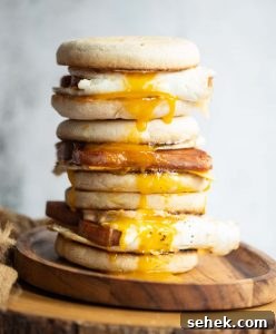 3 sandwiches stacked on each other on wooden board with yolk dripping out