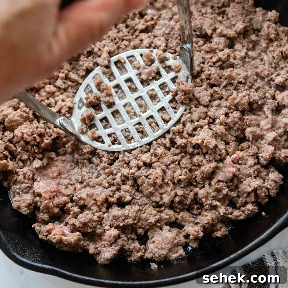 Weeknight Gluten-Free Tacos That Transform Dinner 5 a masher breaking up the ground beef in a skillet.
