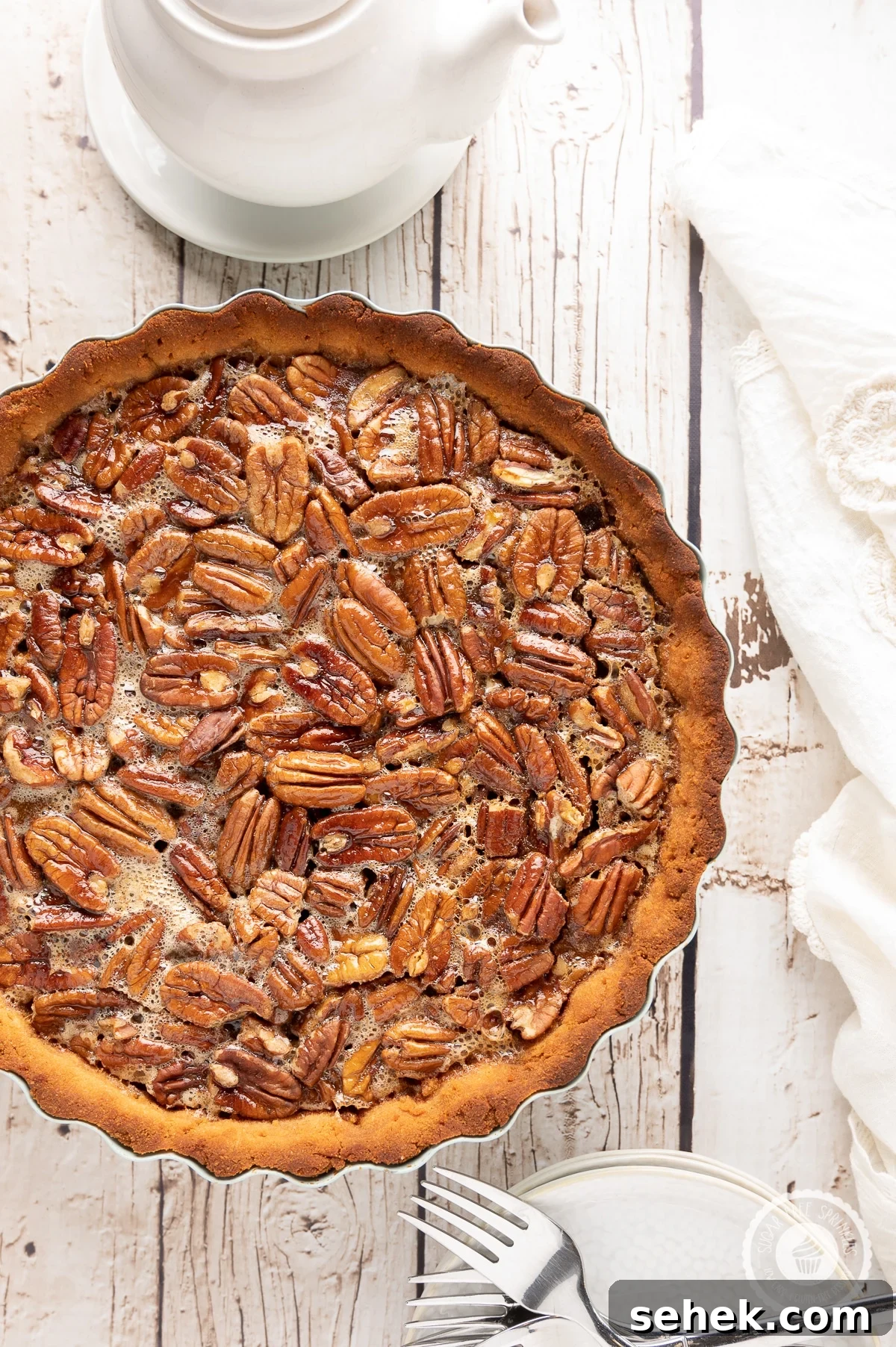 Sticky Sugar-Free Pecan Pie That Stays Gooey Even When Cold 5 Pecan pie on a rustic wooden backdrop with white napkin, plates and a pot of hot tea