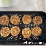 Air Fryer Pillsbury Cinnamon Rolls: Quick & Fluffy Recipe 11 uncooked cinnamon rolls in air fryer basket.