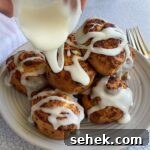 Air Fryer Pillsbury Cinnamon Rolls: Quick & Fluffy Recipe 12 frosting being drizzled on cinnamon rolls.