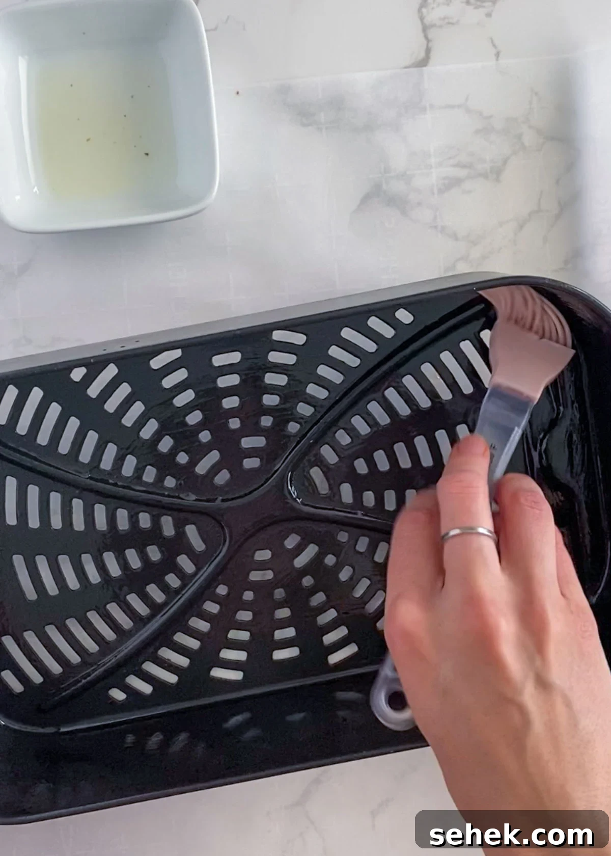 Air Fryer Pillsbury Cinnamon Rolls: Quick & Fluffy Recipe 4 avocado oil being brushed on an air fryer basket.