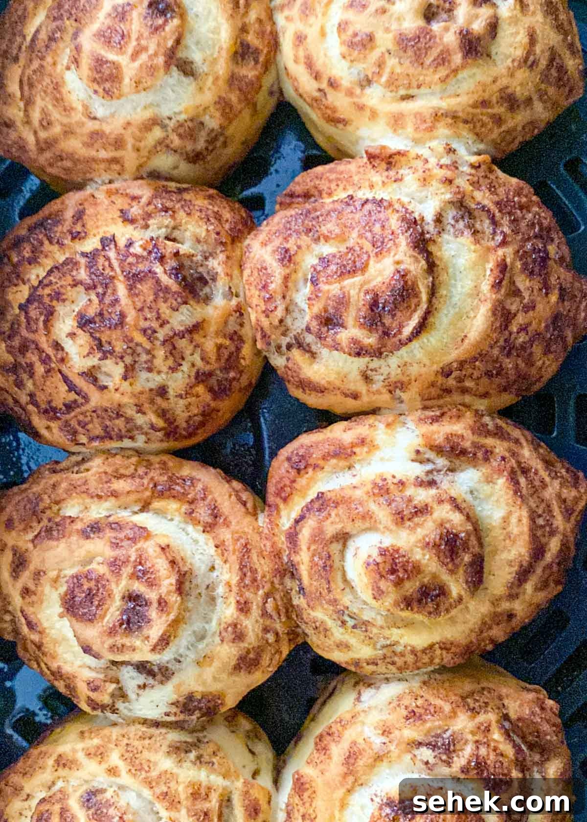 Air Fryer Pillsbury Cinnamon Rolls: Quick & Fluffy Recipe 6 cooked cinnamon rolls in an air fryer basket.