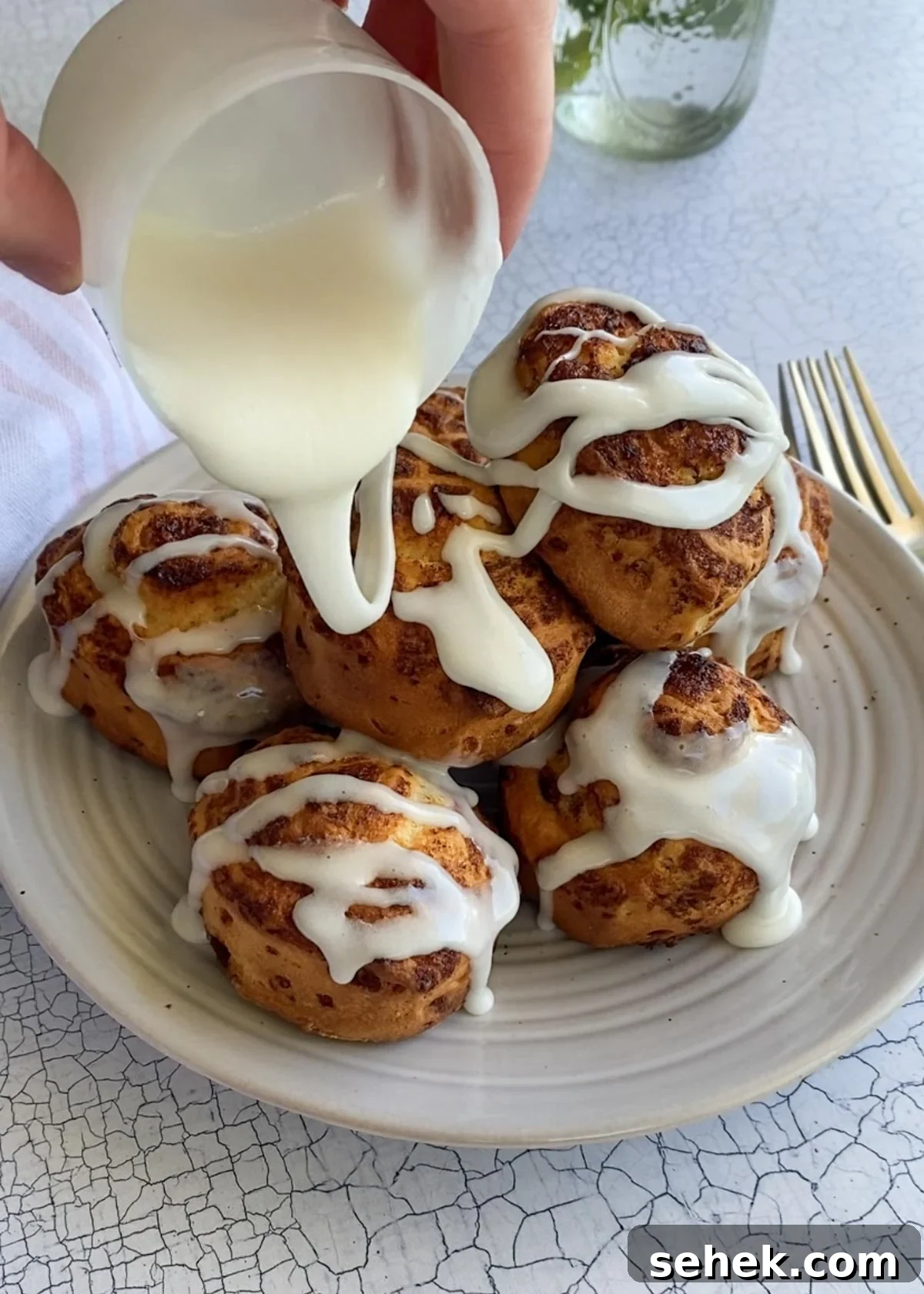 Air Fryer Pillsbury Cinnamon Rolls: Quick & Fluffy Recipe 7 frosting being drizzled on a plate of cinnamon rolls.