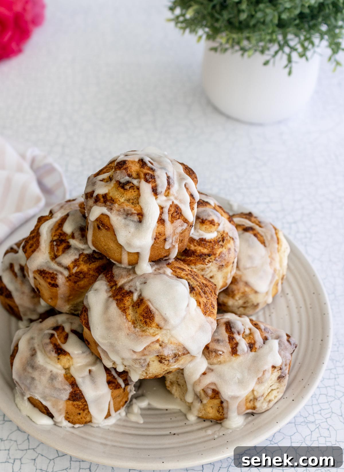 Air Fryer Pillsbury Cinnamon Rolls: Quick & Fluffy Recipe 8 frosted air fryer cinnamon rolls stacked on a plate.