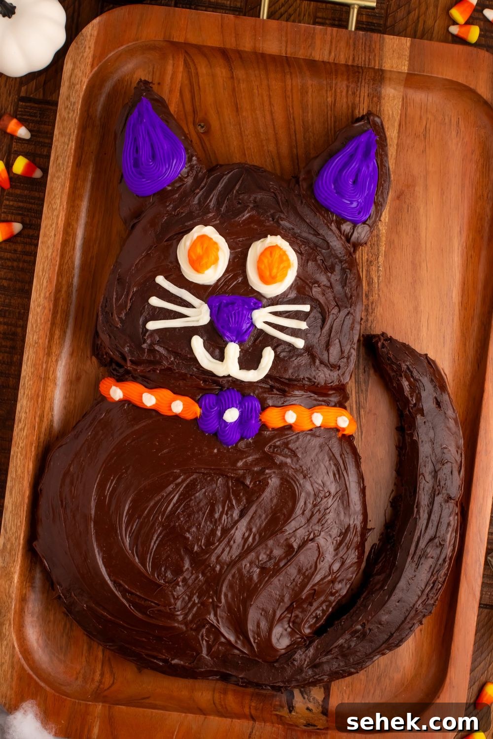 side view of Easy Halloween Black Cat Cut Out Cake on a serving tray with candy corn around it 