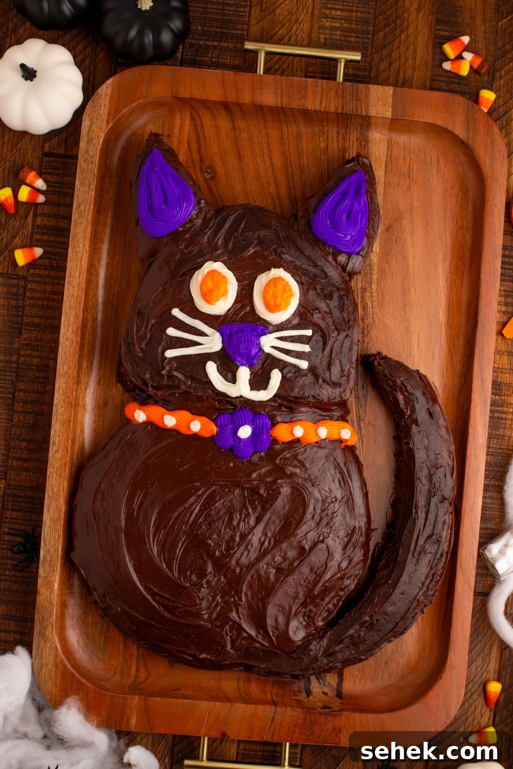 Easy Halloween Black Cat Cut Out Cake on a tray with fake pumpkins around the tray and candy corn candy to side 