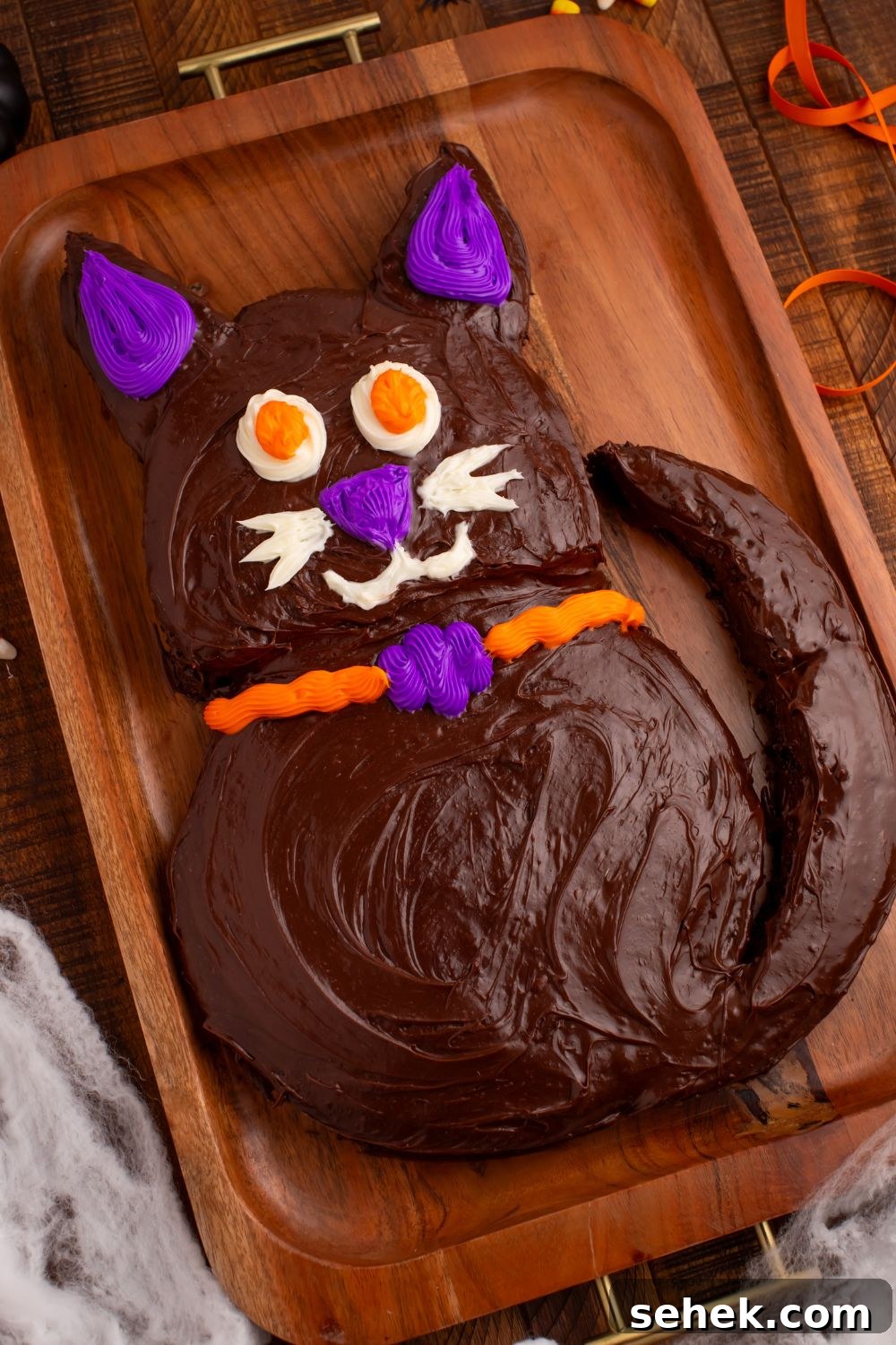 Easy Halloween Black Cat Cut Out Cake on a serving tray with fake spider webs around bottom of tray 