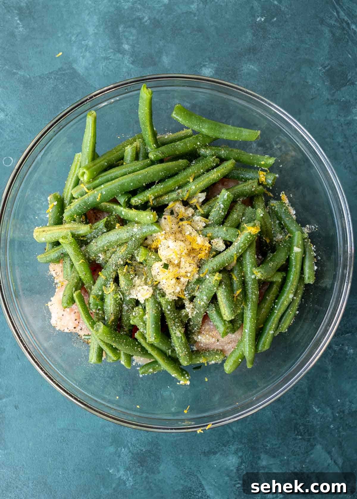 Crispy Lemon Pepper Chicken in the Air Fryer 5 garlic, lemon juice, lemon zest, olive oil, salt, and pepper on top of green beans and chicken in a bowl