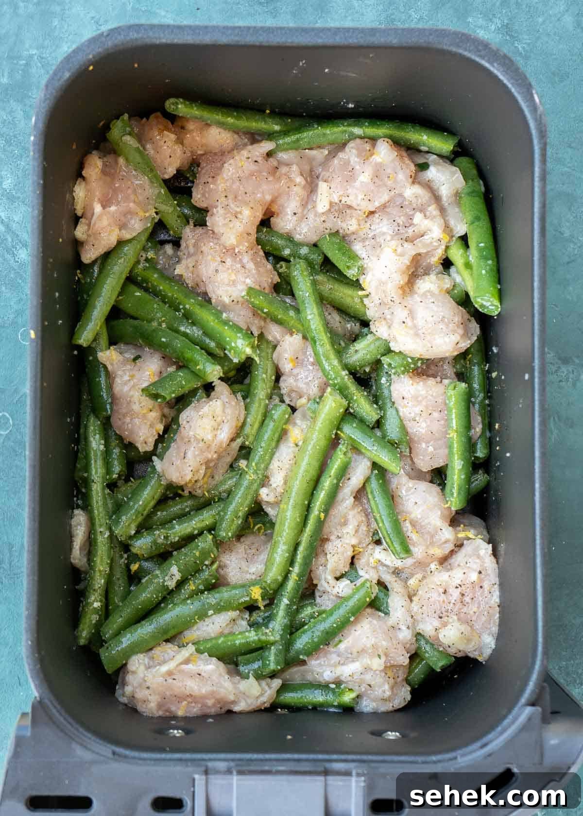 Crispy Lemon Pepper Chicken in the Air Fryer 7 uncooked, seasoned chicken and green beans in the air fryer