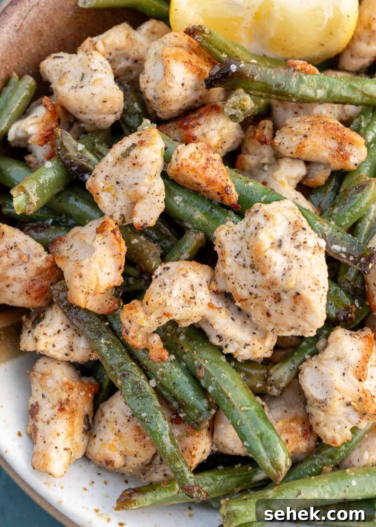 Crispy Lemon Pepper Chicken in the Air Fryer 10 lemon pepper air fryer chicken and veggies in a bowl with lemon wedge