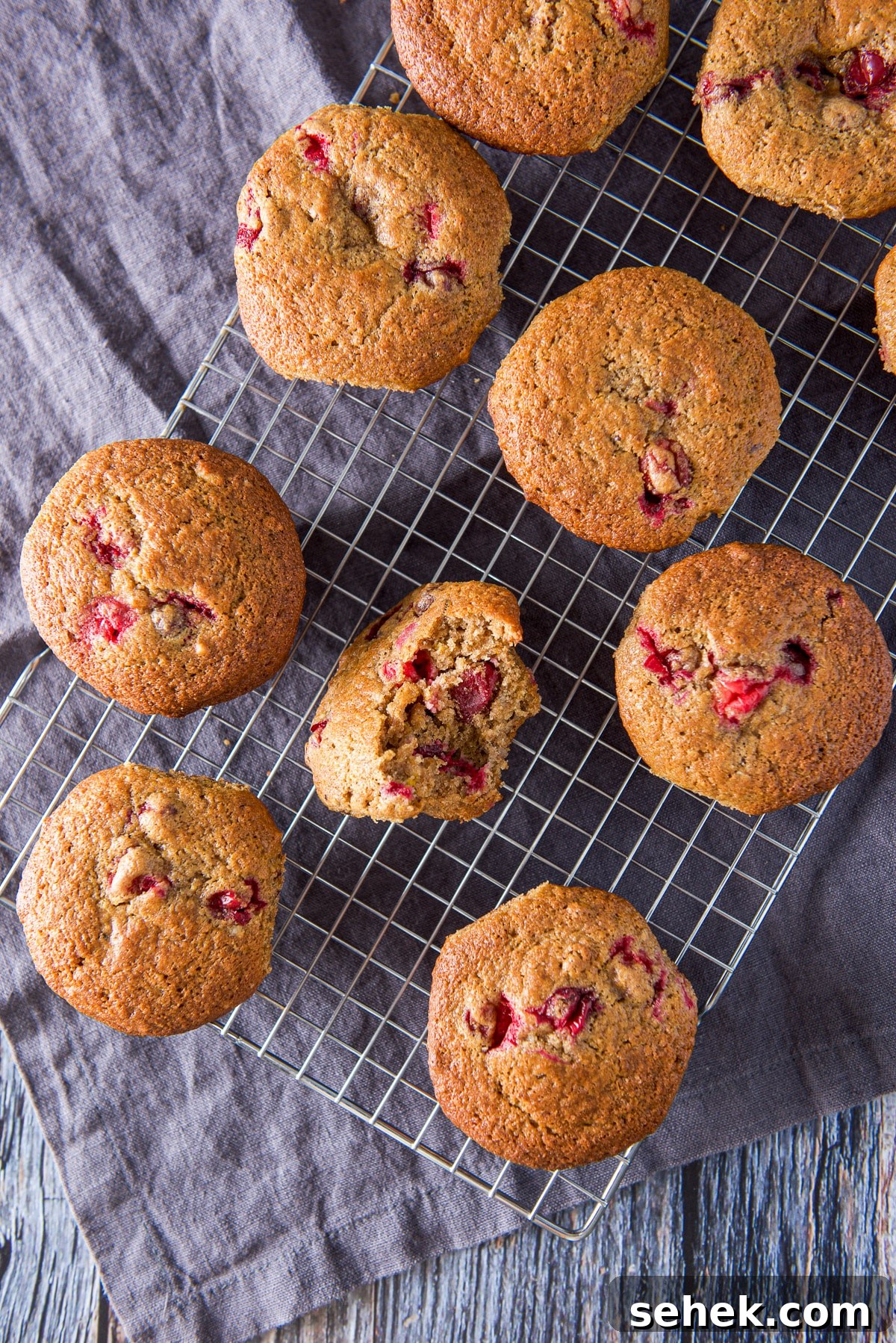 Cranberry Orange Muffins Recipe with Zesty Citrus Glaze 2 Overhead view of the muffins on the wire rack, one of the muffins has a bite taken out of it