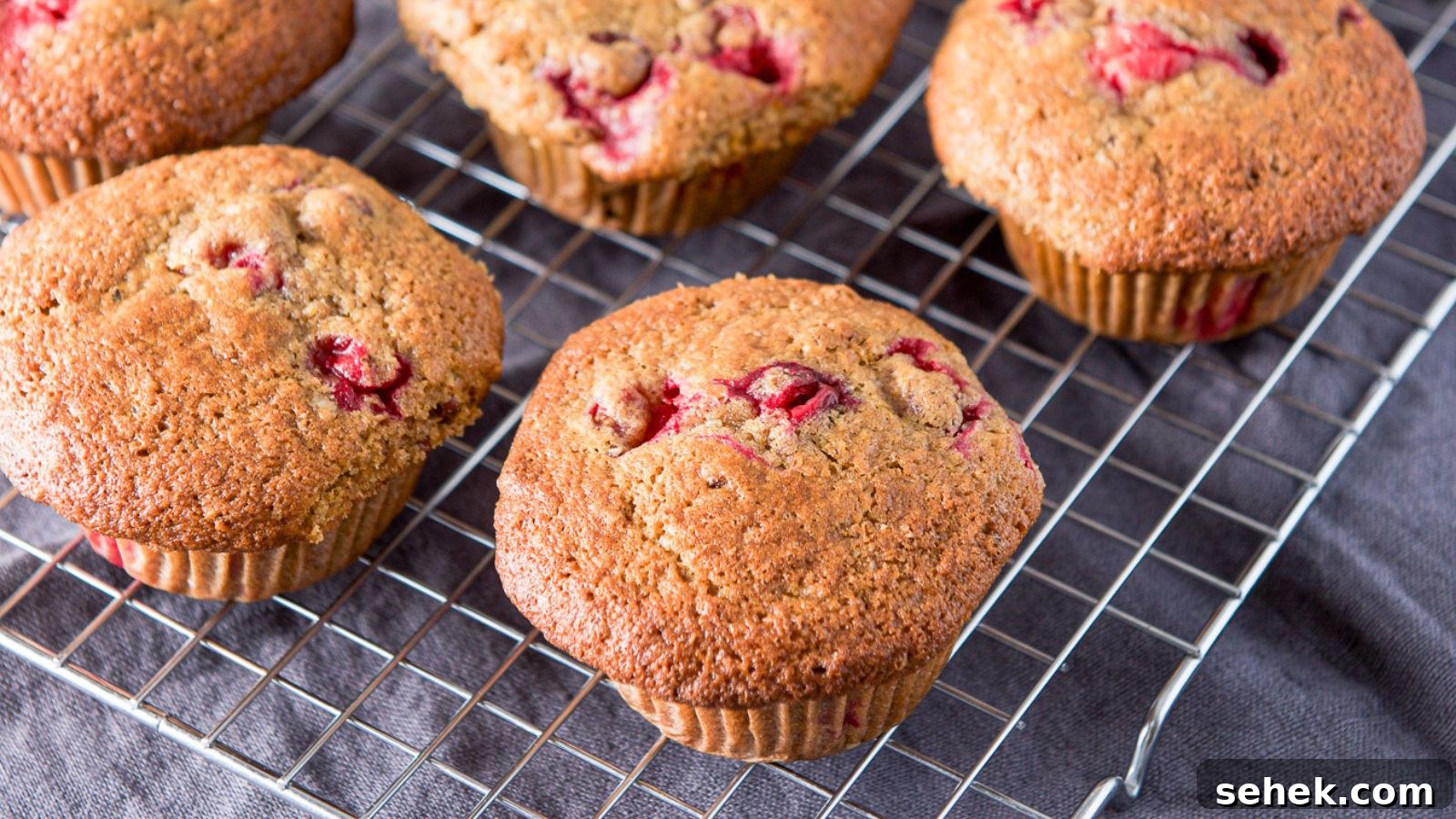 Cranberry Orange Muffins Recipe with Zesty Citrus Glaze 3 A wire rack with muffins on it with cranberries in them