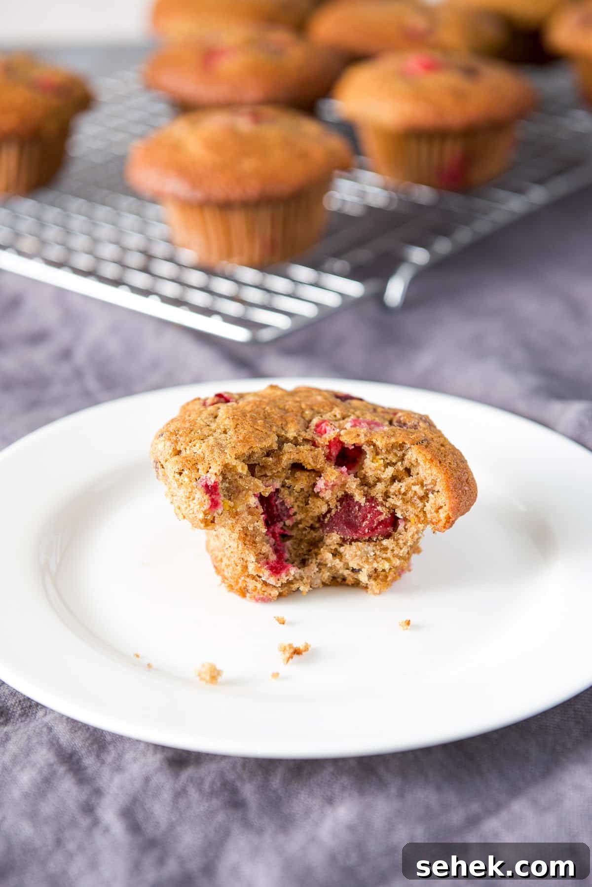 Cranberry Orange Muffins Recipe with Zesty Citrus Glaze 9 A small white plate with a muffin with a bite taken out of it