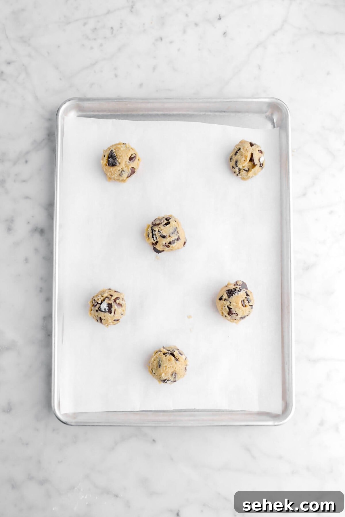 Oreo Chocolate Chip Cookies Recipe — Crispy Cookies with Oreo Chunks 8 six balls of cookie dough on lined parchment paper.