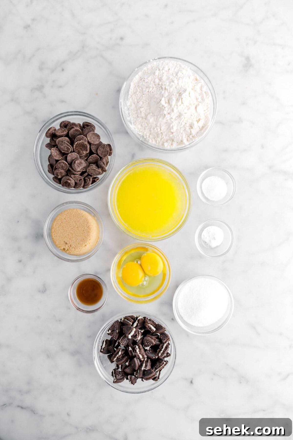 Oreo Chocolate Chip Cookies Recipe — Crispy Cookies with Oreo Chunks 5 flour, chocolate chips, melted butter, salt, baking soda, granulated sugar, chopped oreos, eggs, vanilla, and brown sugar on marble surface.