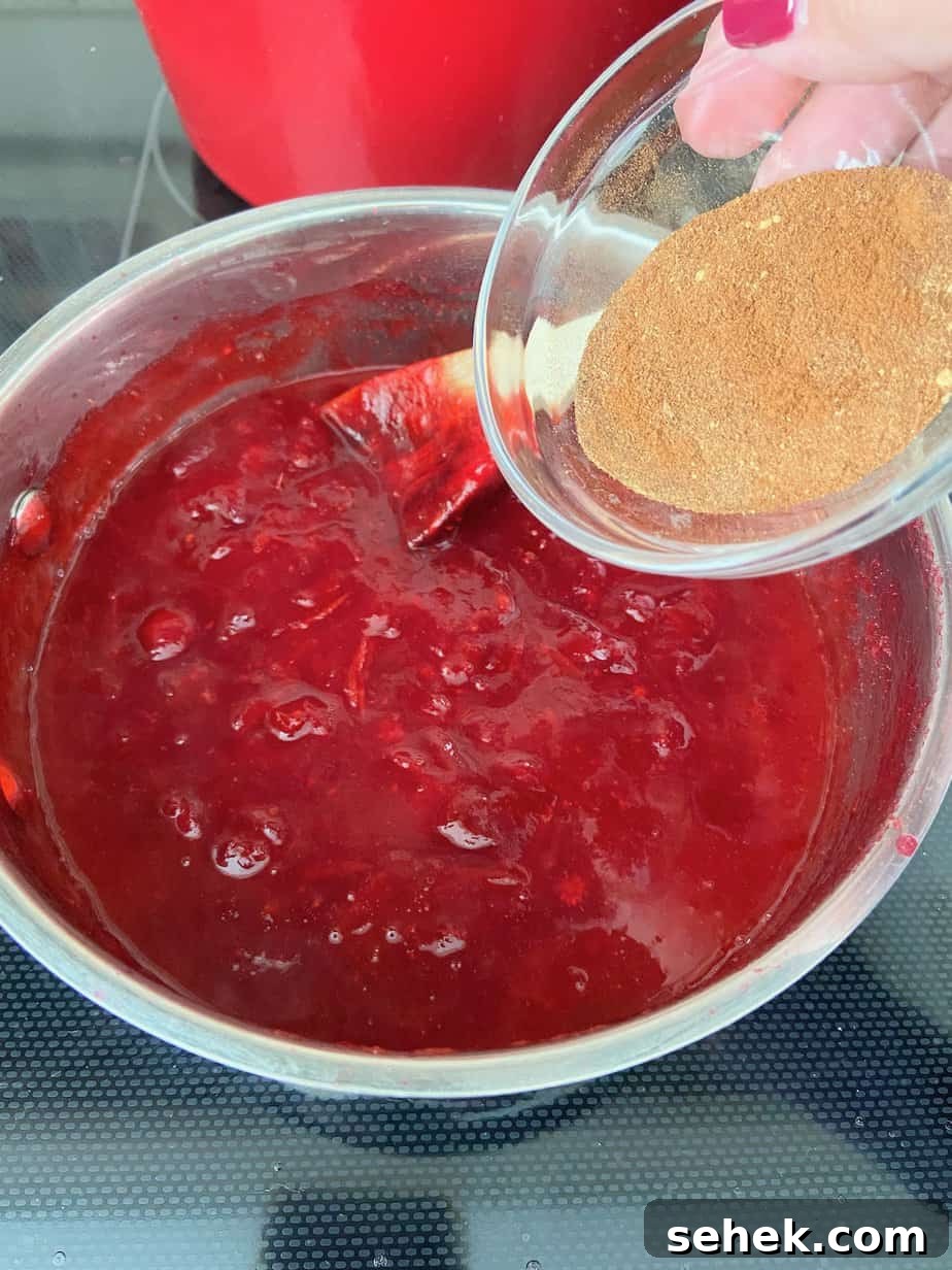 Homemade Spiced Cranberry Sauce with Warm Holiday Spices 6 Spice blend being added to saucepan of cranberries.