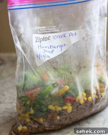 Ingredients for Hamburger soup filling a freezer bag on counter.