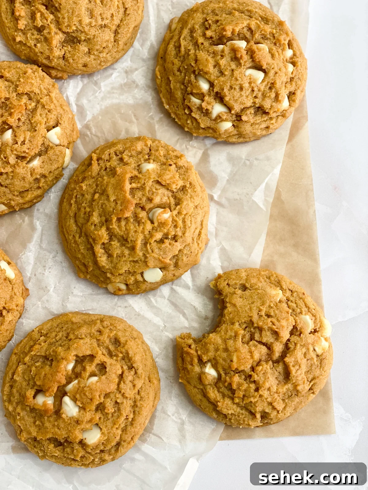 some pumpkin white chocolate chip cookies with a bite missing from one.
