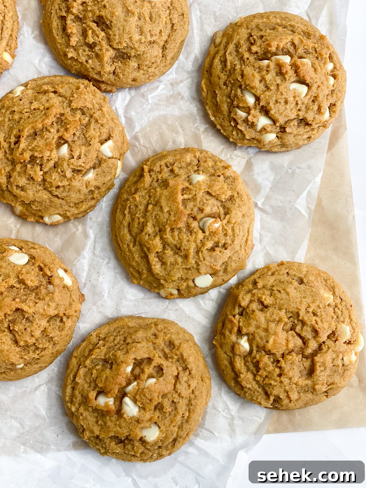 pumpkin white chocolate chip cookies lined up on parchment paper.