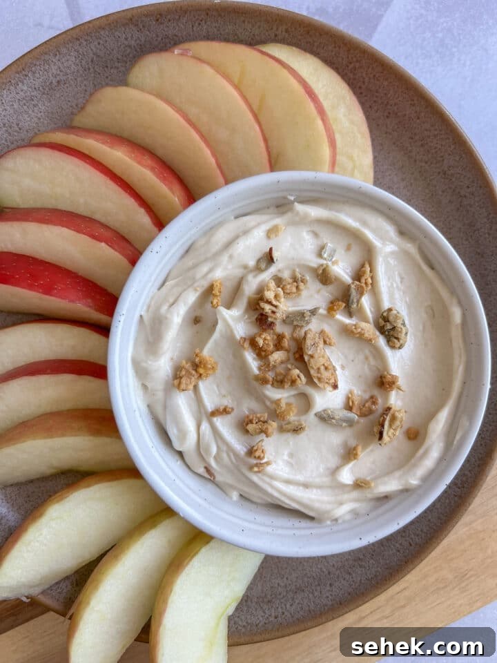 peanut butter yogurt dip topped with granola and paired with apple slices
