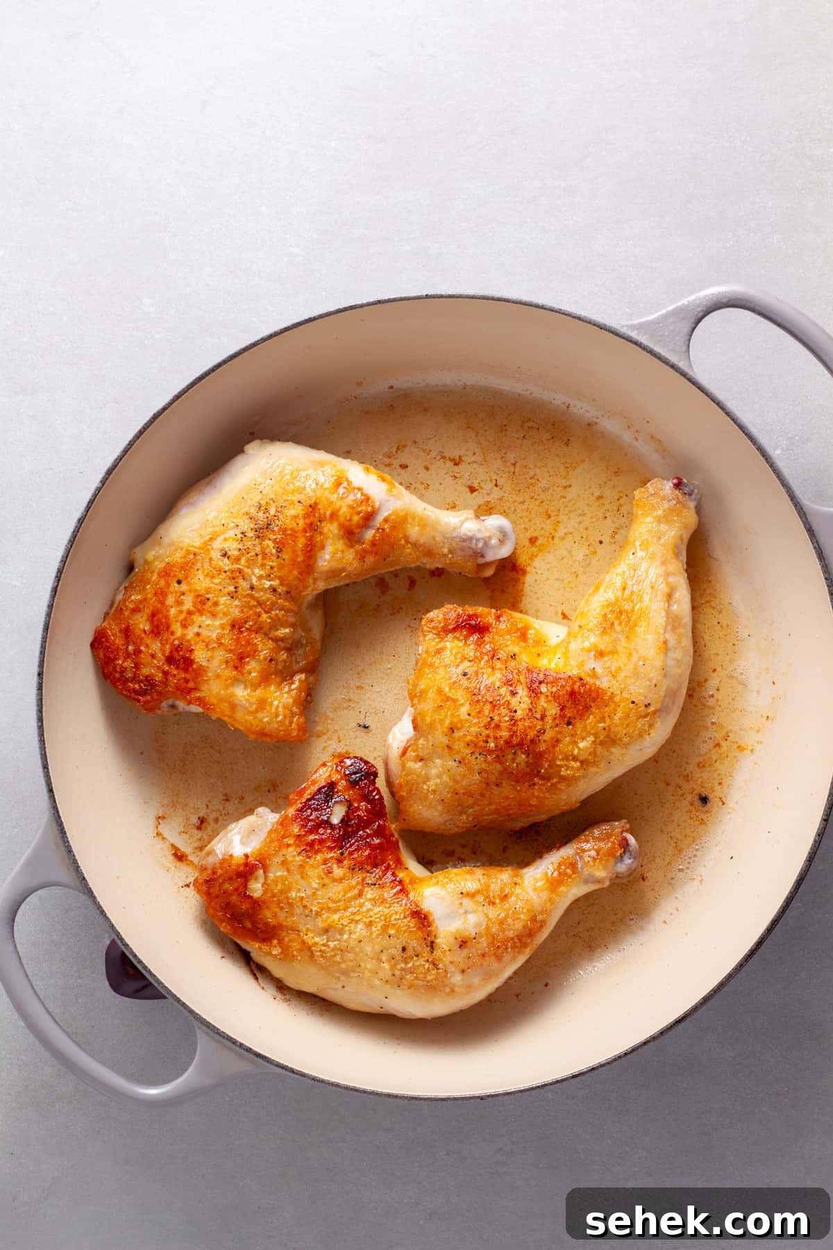 Chicken leg quarters browning in a large skillet.