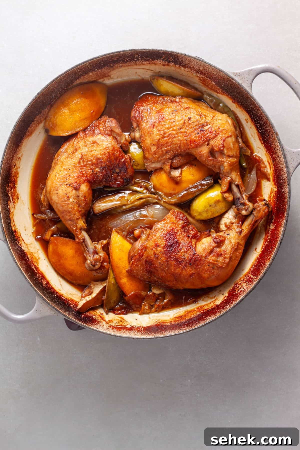 Chicken leg quarters added to a skillet with aromatics for a spicy chicken with ginger, citrus and soy.