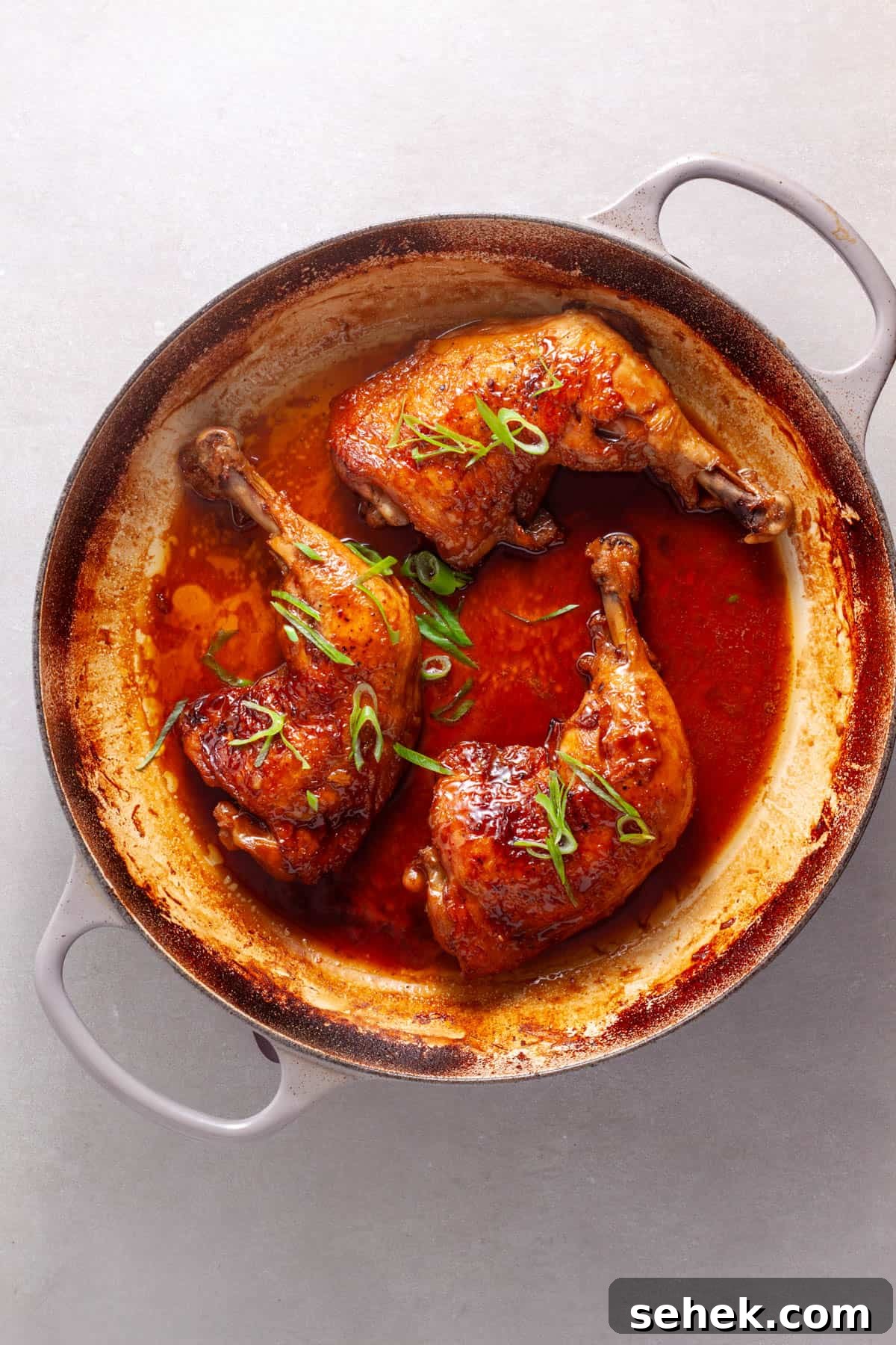 Chicken leg quarters smothered in a spicy ginger, citrus and soy sauce in a large skillet.