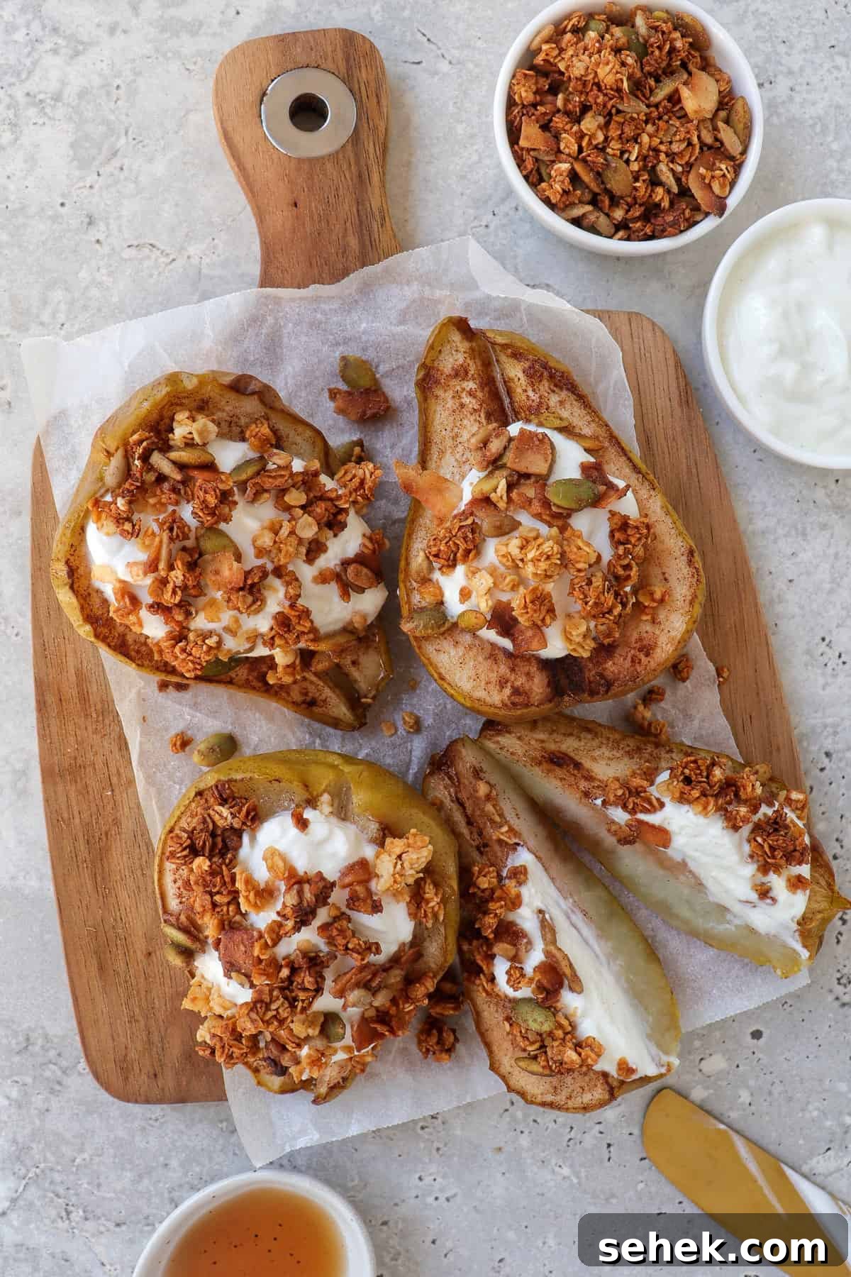 Crispy Cinnamon Air Fryer Pears with Honey Glaze 2 Cooked pears on wooden board topped with plain yoghurt and granola. One pear cut in half.