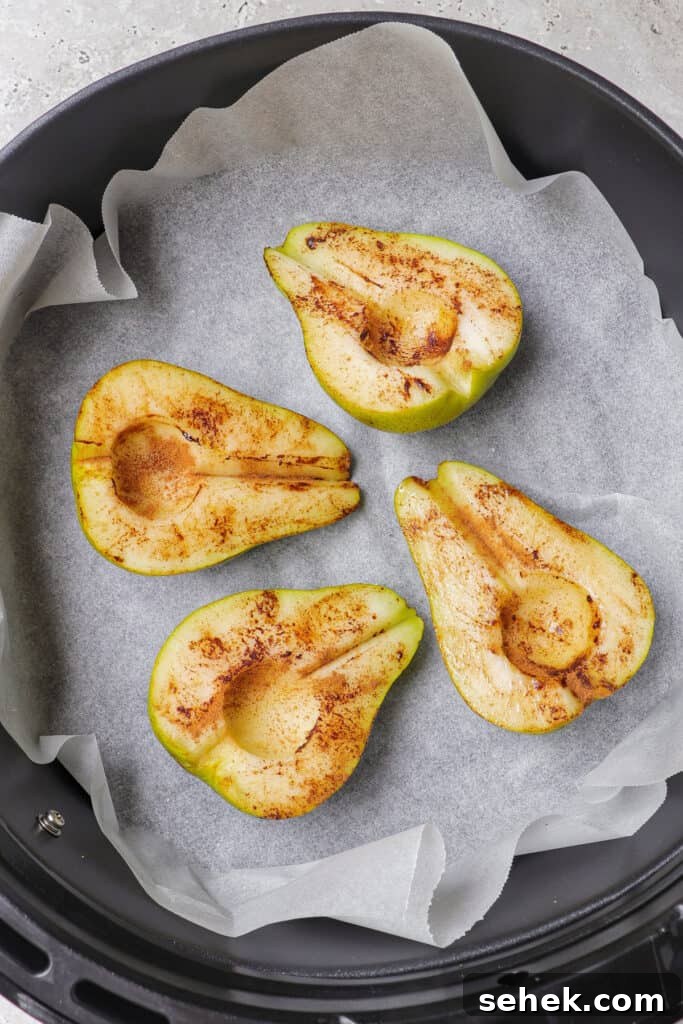 Crispy Cinnamon Air Fryer Pears with Honey Glaze 5 Pears rubbed with cinnamon in air fryer basket.